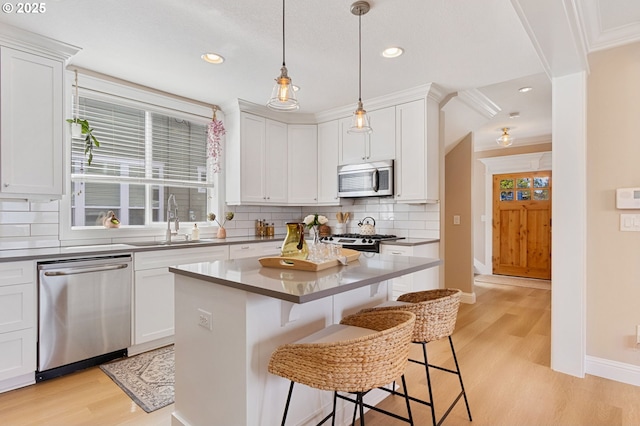 4926 NE 12th Ave, Portland, OR 97211 - kitchen with stainless steel appliances, a sink, light wood-style floors, tasteful backsplash, and a breakfast bar