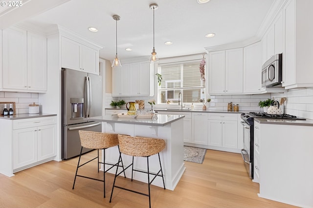 4926 NE 12th Ave, Portland, OR 97211 - kitchen with stainless steel appliances, decorative backsplash, light wood-type flooring, a kitchen bar, and recessed lighting