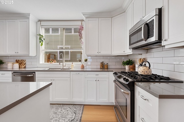 4926 NE 12th Ave, Portland, OR 97211 - kitchen featuring appliances with stainless steel finishes, a sink, white cabinets, and decorative backsplash
