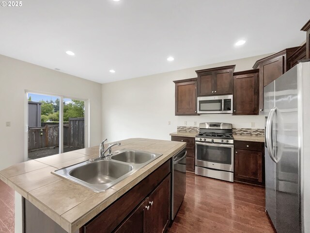 10095 NW Curtis St, North Plains, OR 97133 - kitchen with stainless steel appliances, a sink, dark wood-type flooring, dark brown cabinets, and a center island with sink