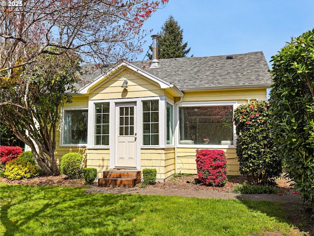 exterior space featuring a shingled roof and a front yard