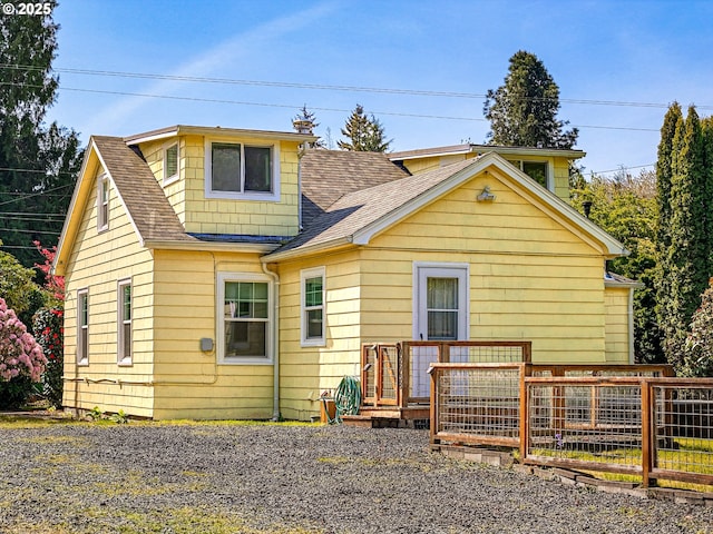 rear view of property featuring a wooden deck and roof with shingles