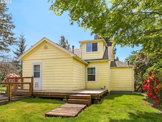 rear view of property with a shingled roof, a wooden deck, and a yard