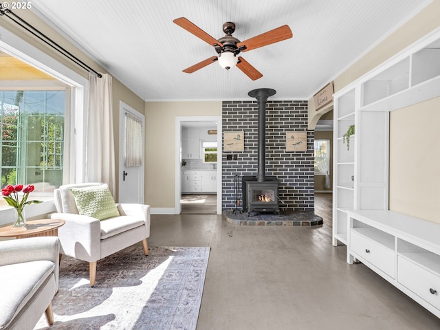 living area featuring a ceiling fan, a wood stove, and finished concrete floors