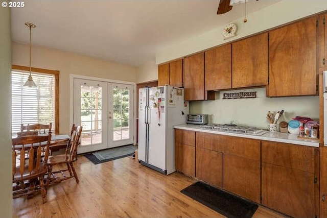 22885 S Tendril Ln, West Linn, OR 97068 - kitchen featuring freestanding refrigerator, brown cabinetry, light countertops, light wood-style floors, and stainless steel gas cooktop