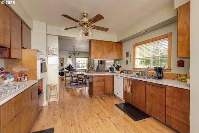 22885 S Tendril Ln, West Linn, OR 97068 - kitchen with a sink, brown cabinetry, ceiling fan, white dishwasher, and light wood-style floors