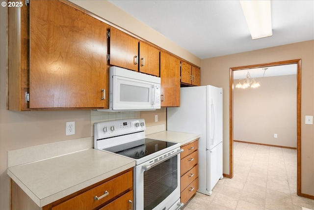 kitchen with brown cabinets, light floors, light countertops, white appliances, and baseboards