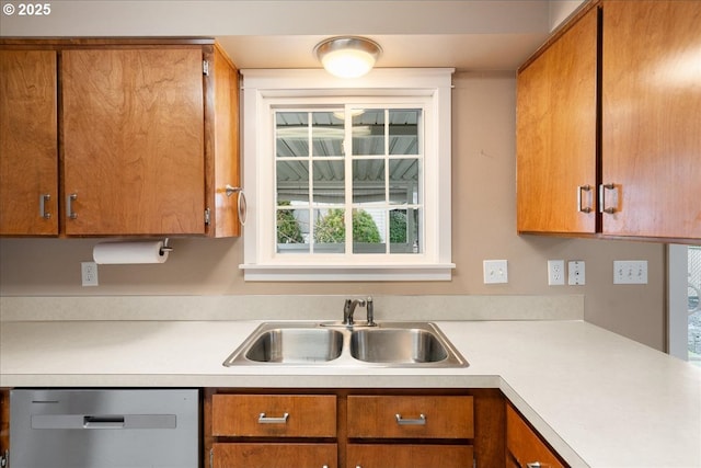 kitchen featuring brown cabinetry, light countertops, dishwasher, and a sink