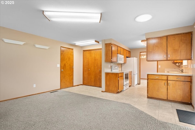 kitchen featuring white appliances, light countertops, a sink, and light carpet