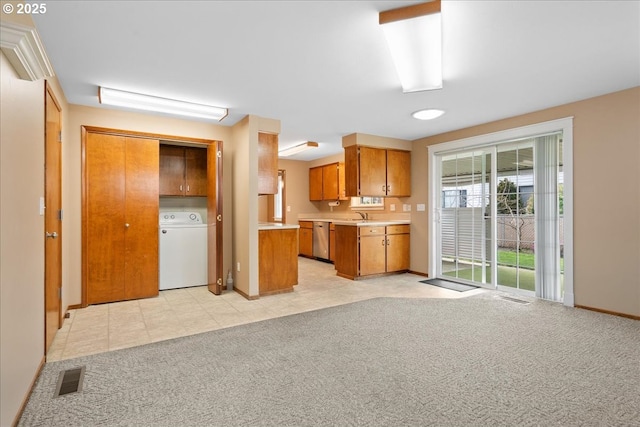 kitchen featuring washer / dryer, visible vents, brown cabinetry, light colored carpet, and light countertops