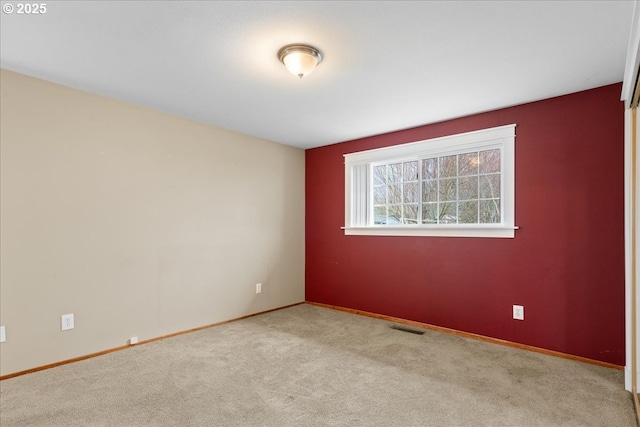 spare room with carpet, visible vents, and baseboards