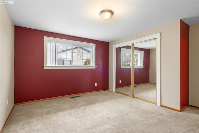 unfurnished bedroom with a closet, carpet, visible vents, and baseboards