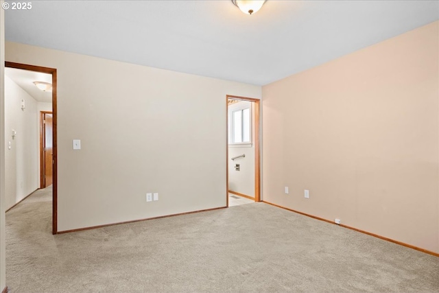 empty room featuring light carpet and baseboards