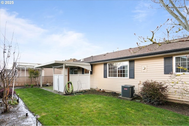 back of property with central AC, a lawn, and fence