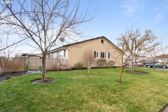 view of side of home with fence and a lawn