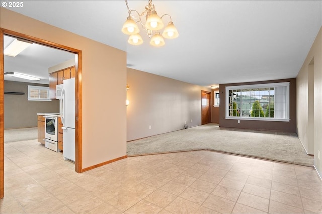 empty room featuring a chandelier, baseboards, and light colored carpet