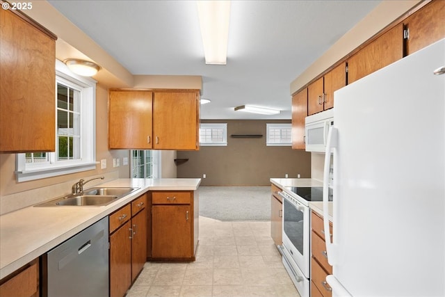 kitchen featuring brown cabinets, white appliances, light countertops, and a sink