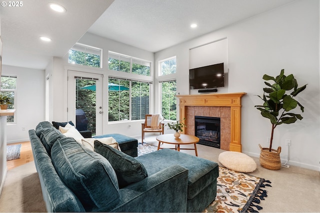 carpeted living area featuring baseboards, a tiled fireplace, and recessed lighting