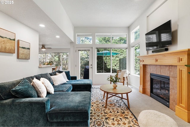 living room with baseboards, a tile fireplace, a textured ceiling, carpet flooring, and recessed lighting