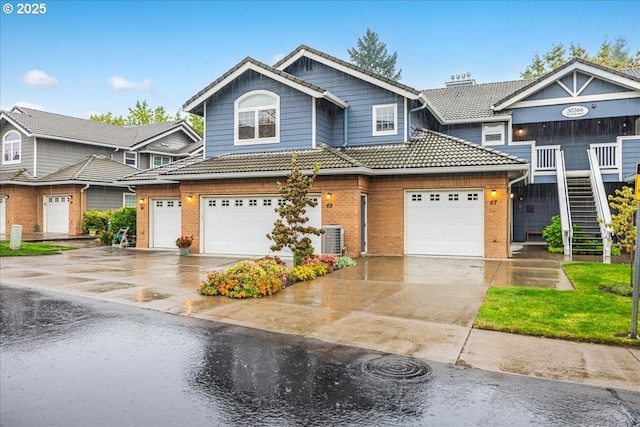 view of front of house featuring brick siding, a tiled roof, driveway, and central AC