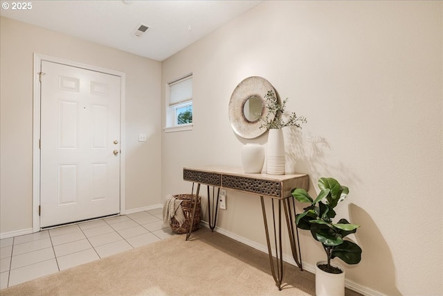 entrance foyer with visible vents, light tile patterned floors, light colored carpet, and baseboards