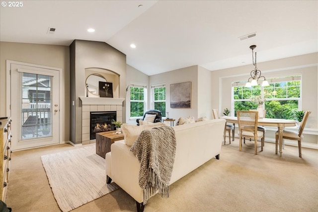 living area with visible vents, lofted ceiling, recessed lighting, a tiled fireplace, and light colored carpet