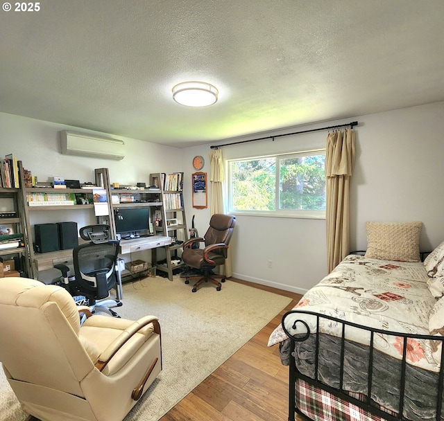 97640 Kadora Ln, North Bend, OR 97459 - bedroom featuring a wall mounted air conditioner, wood finished floors, a textured ceiling, an office area, and baseboards