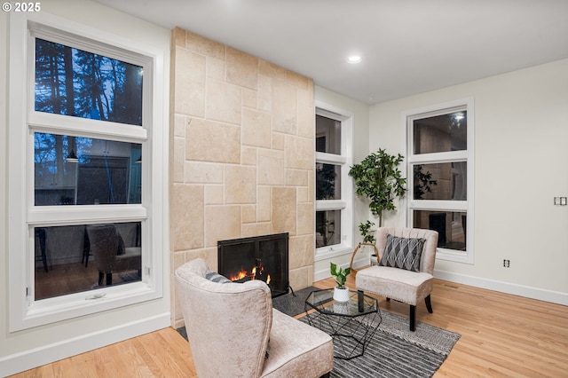 living area featuring a tiled fireplace, hardwood / wood-style flooring, and built in shelves