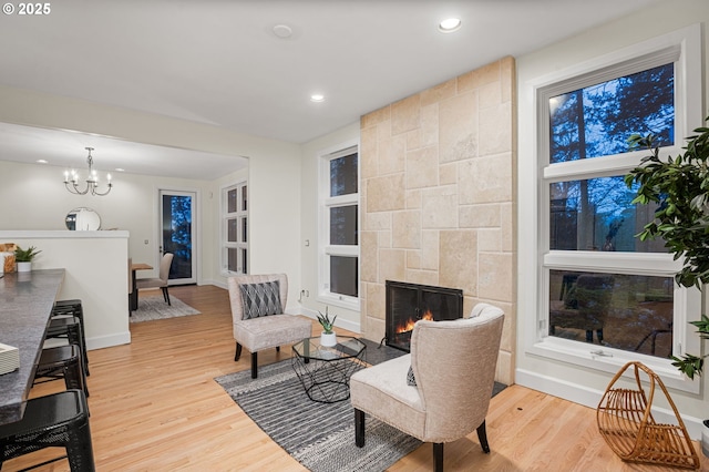 living room featuring a chandelier, a tile fireplace, and light wood-type flooring