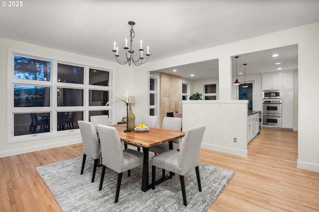 dining area with a notable chandelier, recessed lighting, light wood-type flooring, and baseboards