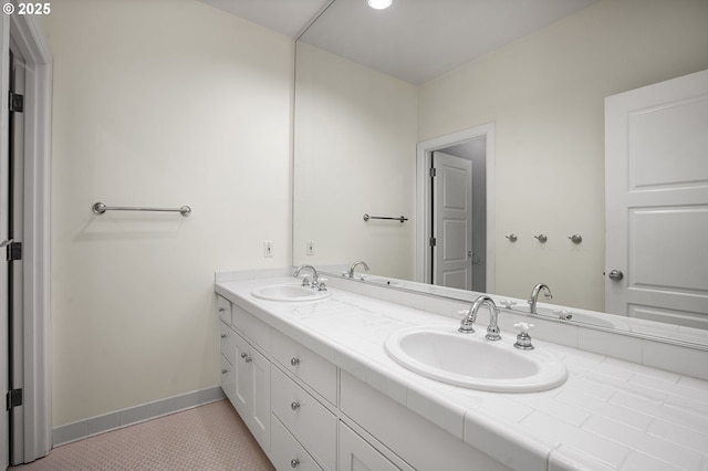 full bath with a sink, baseboards, double vanity, and tile patterned floors