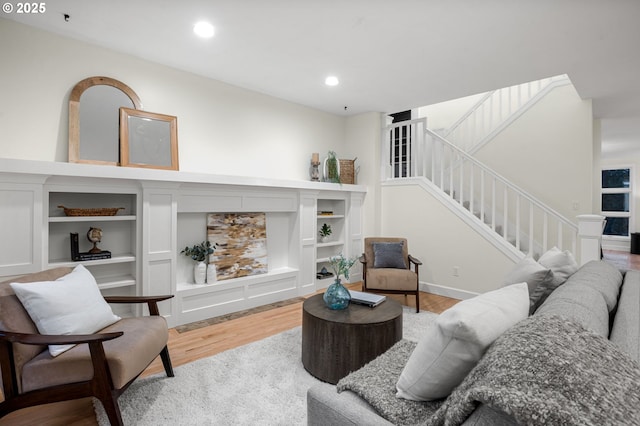 living room featuring a fireplace, stairway, recessed lighting, and wood finished floors