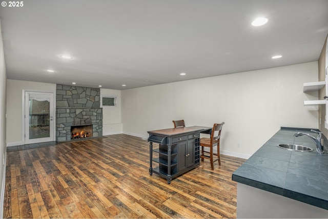 living room with sink, dark wood-type flooring, and a fireplace