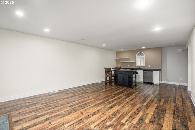 kitchen with stainless steel dishwasher, dark wood-type flooring, recessed lighting, and dark countertops