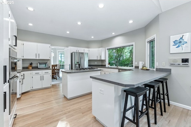 10585 SW 161st Ct, Beaverton, OR 97007 - kitchen featuring stainless steel appliances, a peninsula, recessed lighting, light wood-type flooring, and dark countertops
