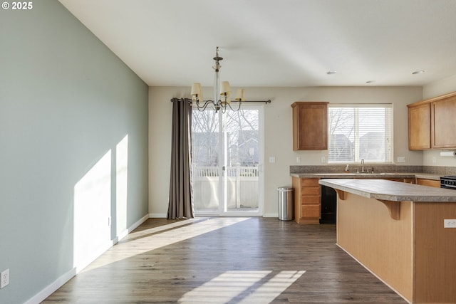 kitchen with dark hardwood / wood-style floors, pendant lighting, sink, a chandelier, and a kitchen bar