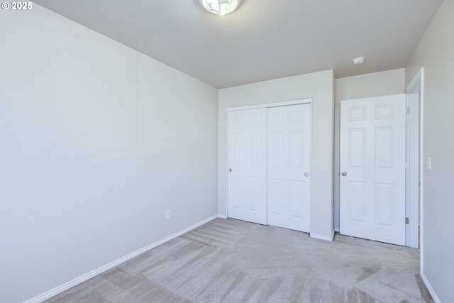 unfurnished bedroom with a closet, light carpet, and a textured ceiling