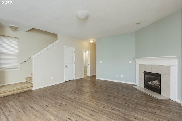 unfurnished living room featuring hardwood / wood-style floors and a tile fireplace