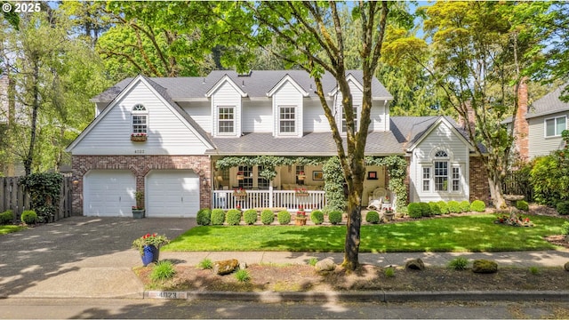 view of front of home featuring brick siding, a garage, a porch, a front yard, and driveway