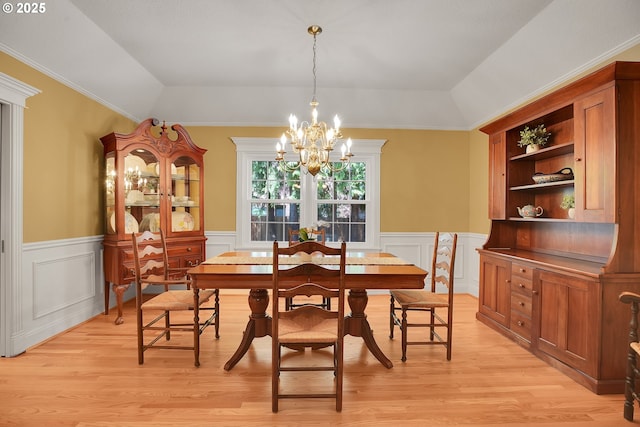 dining room with a wainscoted wall, a tray ceiling, light wood-style flooring, and a chandelier