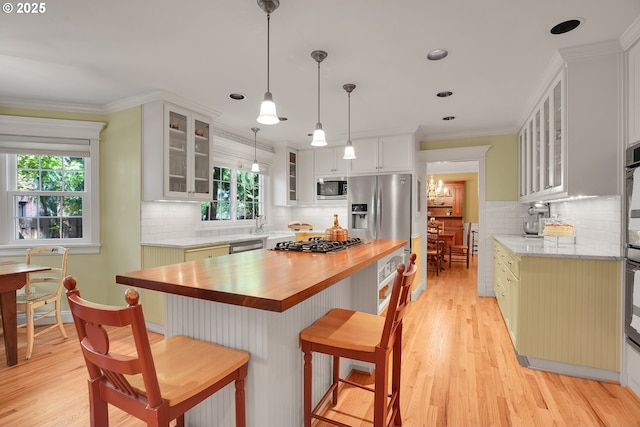 kitchen featuring light wood-style flooring, butcher block counters, tasteful backsplash, and stainless steel appliances