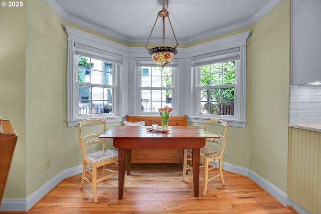 dining space featuring crown molding, baseboards, and light wood-style flooring