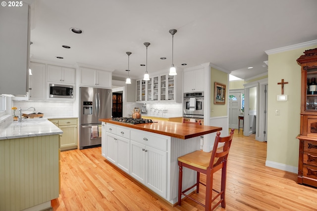 kitchen featuring light wood-style flooring, appliances with stainless steel finishes, backsplash, and wooden counters