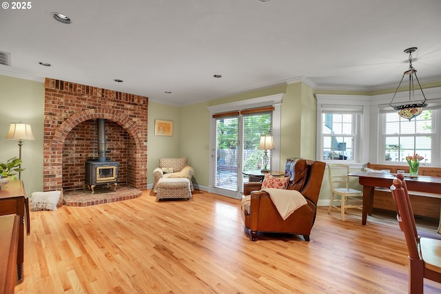 sitting room featuring visible vents, a wood stove, baseboards, and wood finished floors