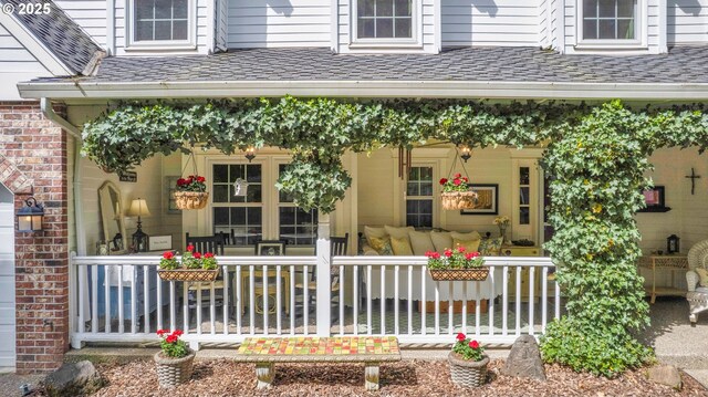 doorway to property with a porch and roof with shingles
