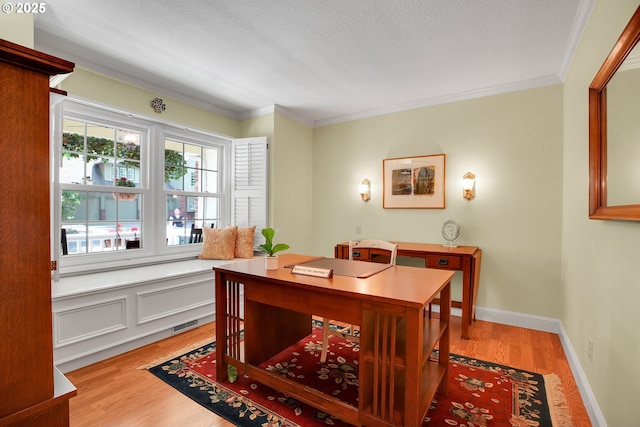 dining space with light wood-type flooring, ornamental molding, and a textured ceiling