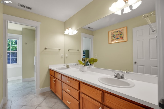 bathroom featuring a sink, baseboards, double vanity, and visible vents