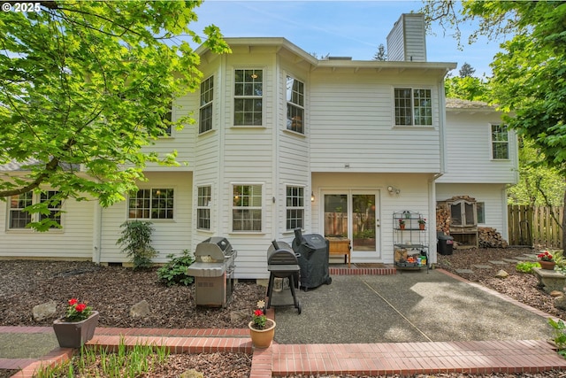 back of property featuring a patio, fence, and a chimney