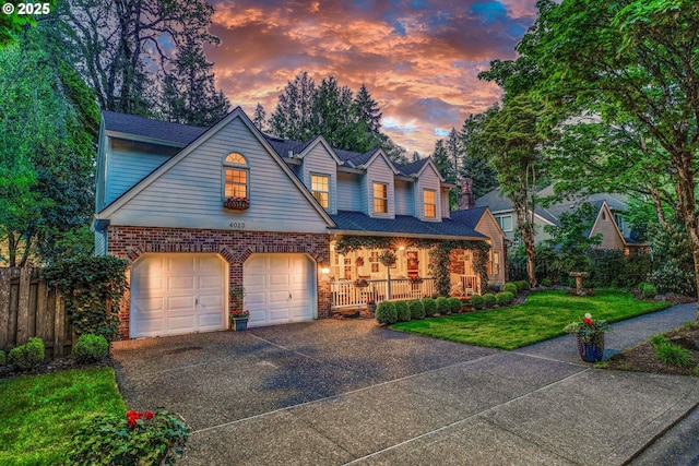 traditional-style house with fence, a front lawn, brick siding, covered porch, and driveway