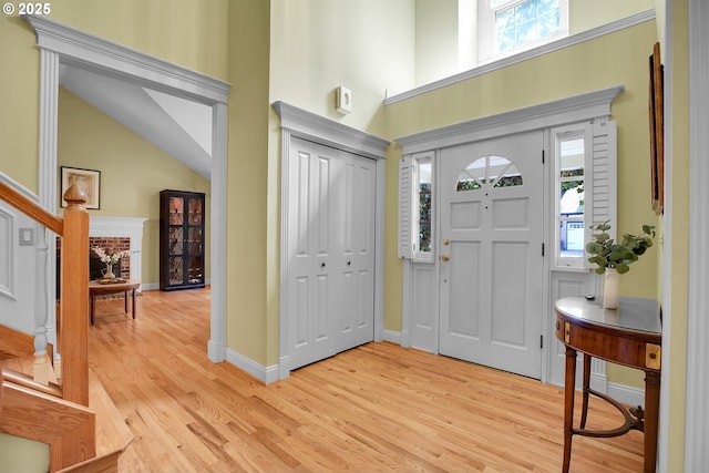 foyer with light wood-style floors, a high ceiling, and stairs